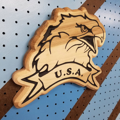 Angled shot of a Handcrafted relief-carved hardwood USA Eagle sign, featuring a detailed eagle design and "U.S.A." text