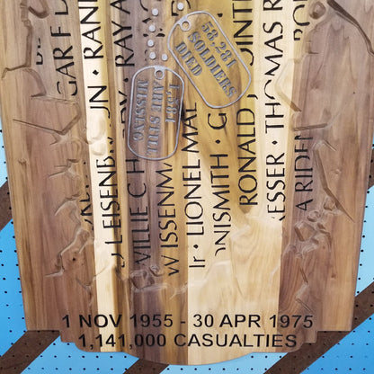 Close-up of custom hardwood Vietnam War memorial sign with carved service dates, casualty count, and dog tag.