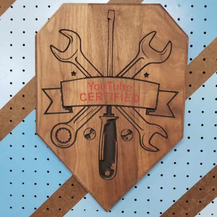 Front view of a custom hardwood wrench driver garage sign with YouTube Certified relief carving on a shop pegboard.